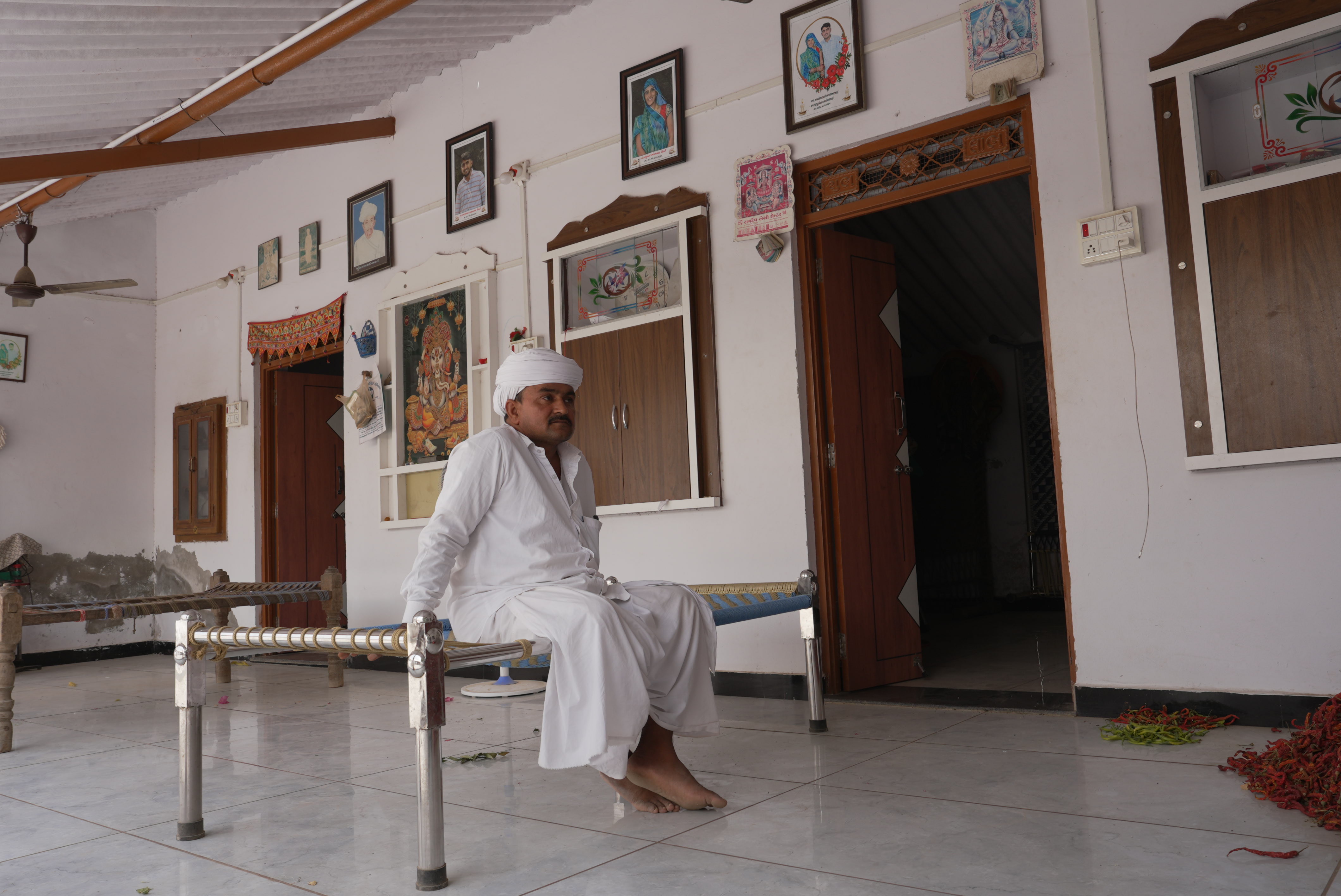 Man wearing white turban and loose shirt and pants sitting on an Indian jute thread bed.