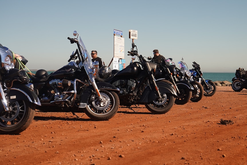Several motorbikes are parked in a row at a near a beach in Western Australia's Pilbara region.