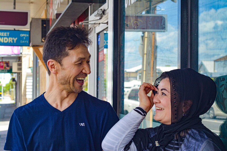 Dawut Sidik and his wife Roshan stand outside their Uyghur restaurant, Karlaylisi, in Footscray. They're smiling at each other.