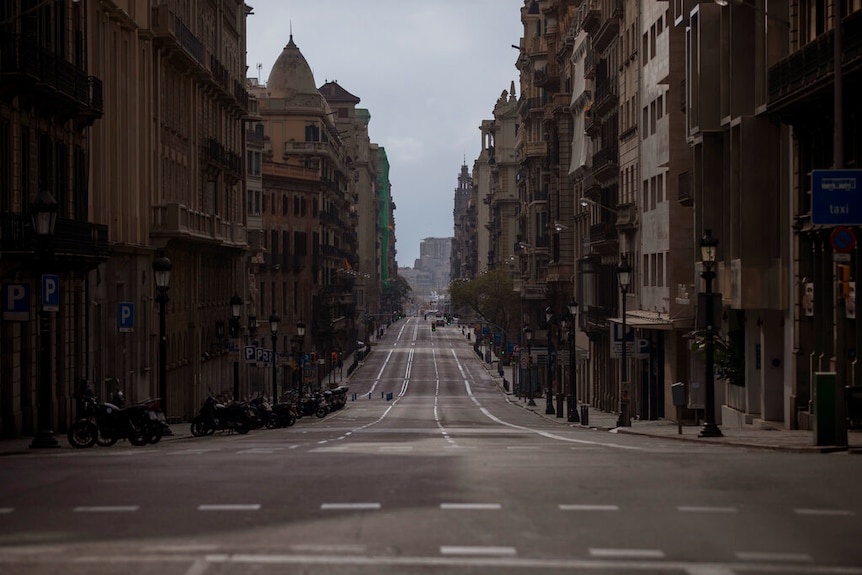 You look down a sloping street of an empty Barcelona street on an overcast day.