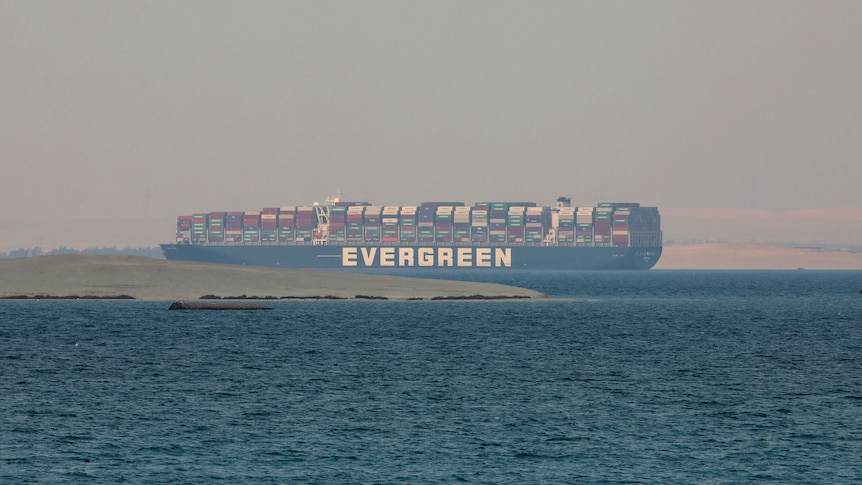 A loaded container ship is seen sitting in a lake between flat expanses of parched land.