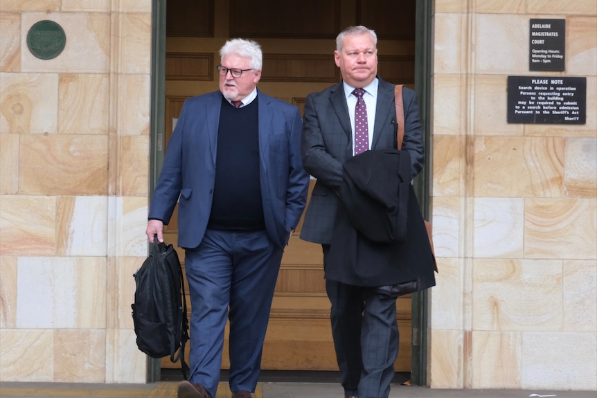 Two men in suits walking out of a court building