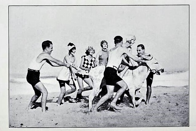 A black-and-white screenshot of a film scene where people in bathers in the 1920s are on the beach.