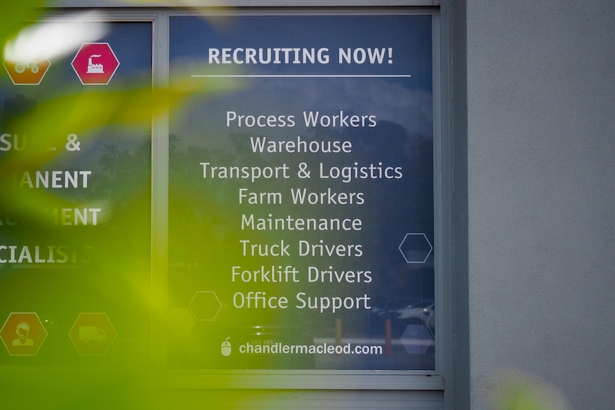 A sign in a shop front saying Recruiting Now!