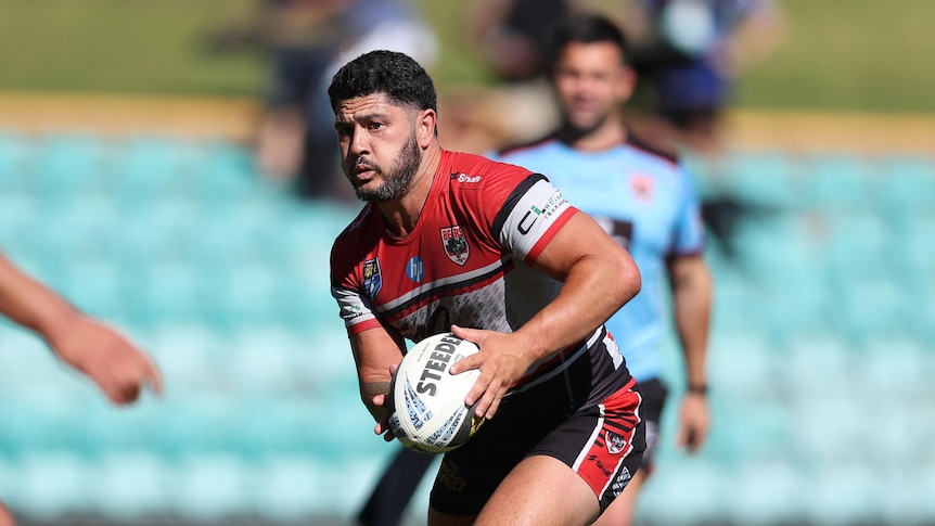 A man runs the ball during a rugby league match