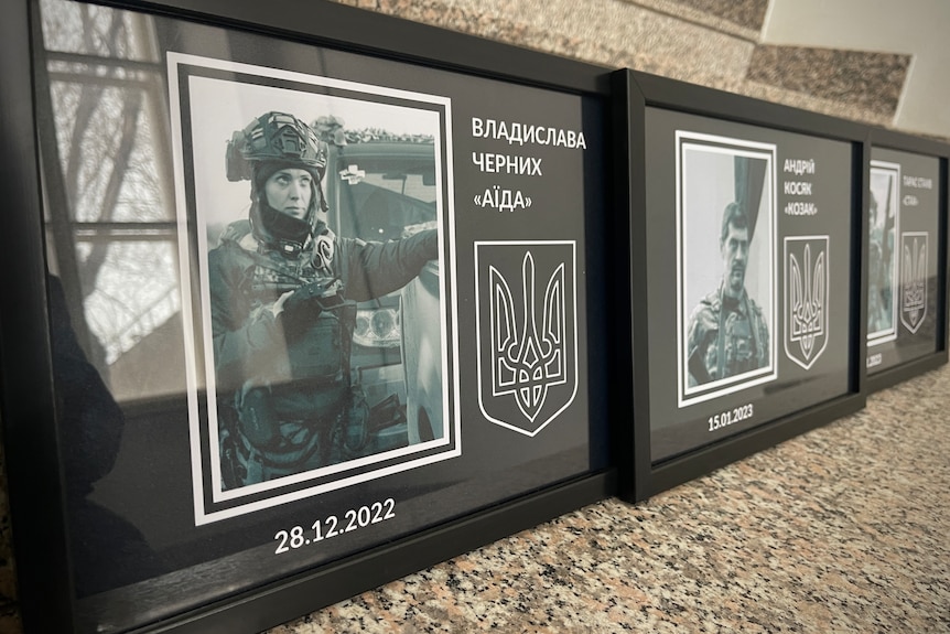 A close up of framed photos along a wall including a black and white photograph of a woman in fatigues.