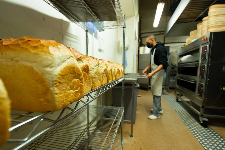 A baker tends to bread in a bakery.