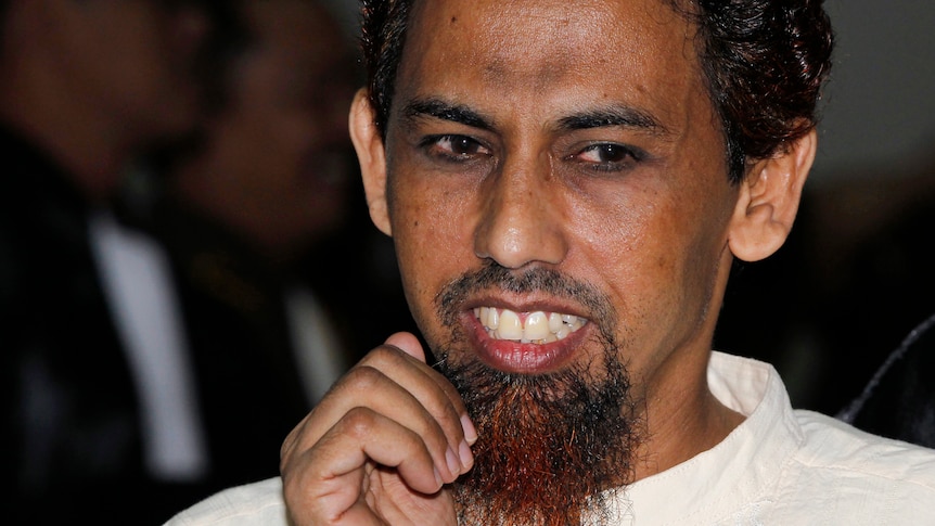 A close up of a man with dark eyes and a goatee.