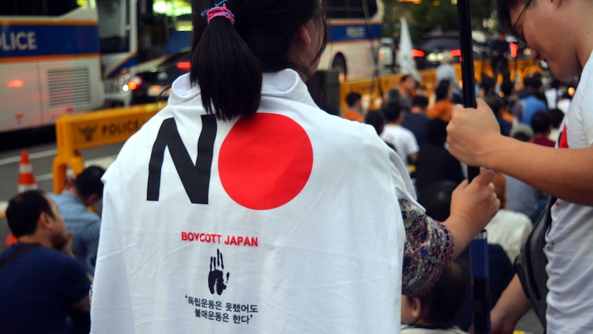 A woman pictured from the back with a 'Boycott Japan' t-shirt draped over her shoulders.