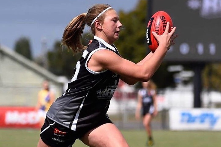 A female footballer grabs the ball while running