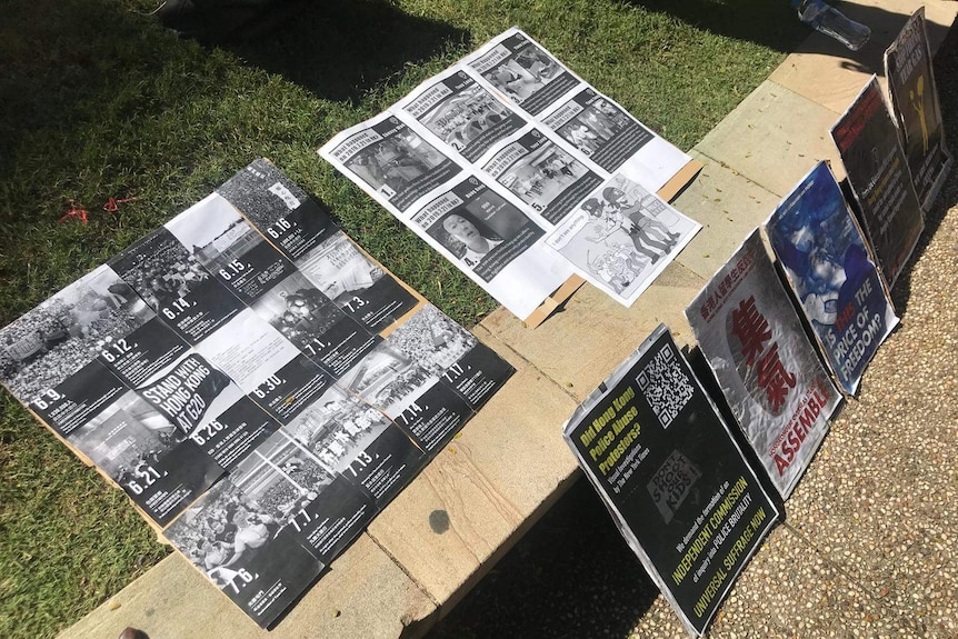 Photos and news articles about protests in Hong Kong are displayed on the sidewalk.