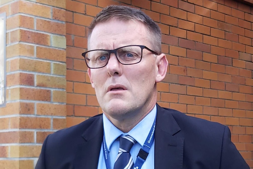 A plain-clothes detective speaking to the media outside a police station