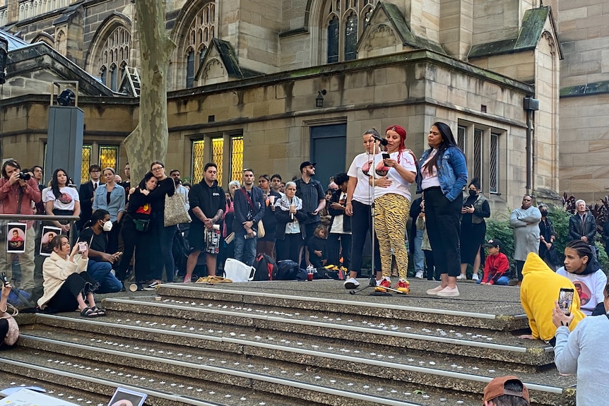 Une femme parle dans un micro alors qu'elle est entourée d'une grande foule.