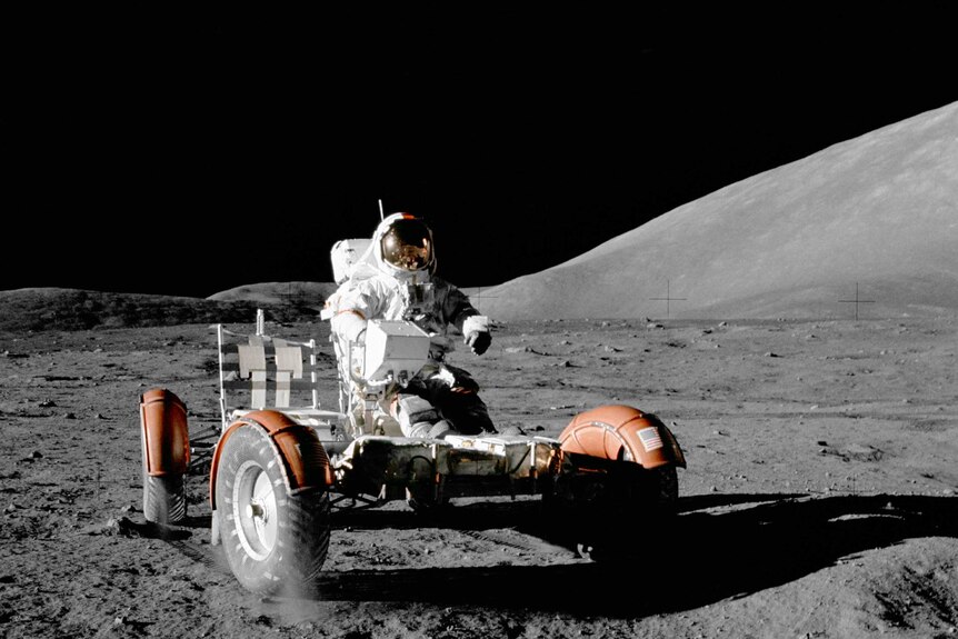 Astronaut Gene Cernan sits in the driver seat of the Lunar Rover while on the surface of the Moon.