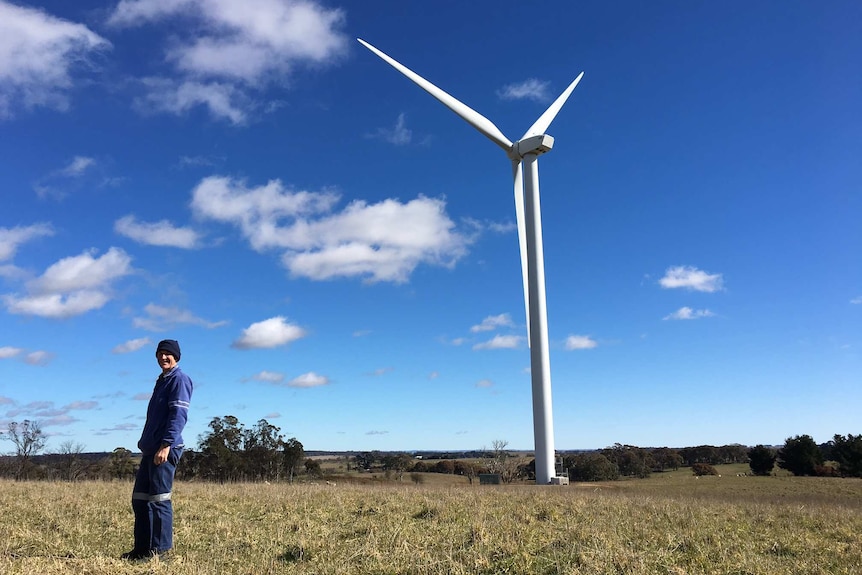 Farmer Carl Banfield standing in front of a wind turbine on his property near Crookwell.