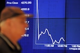 Passers-by watch the share market plunge on an Australian Stock Exchange graph in Sydney