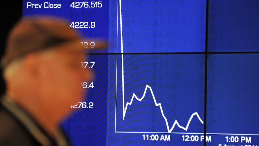 Passers-by watch the share market plunge on an Australian Stock Exchange graph in Sydney.