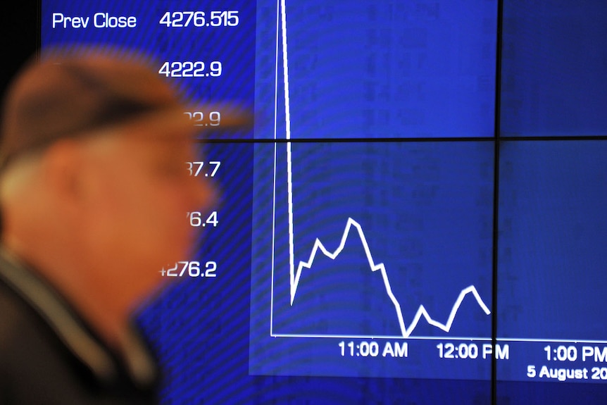 Passers-by watch the share market plunge on an Australian Stock Exchange graph in Sydney on August 5, 2011.