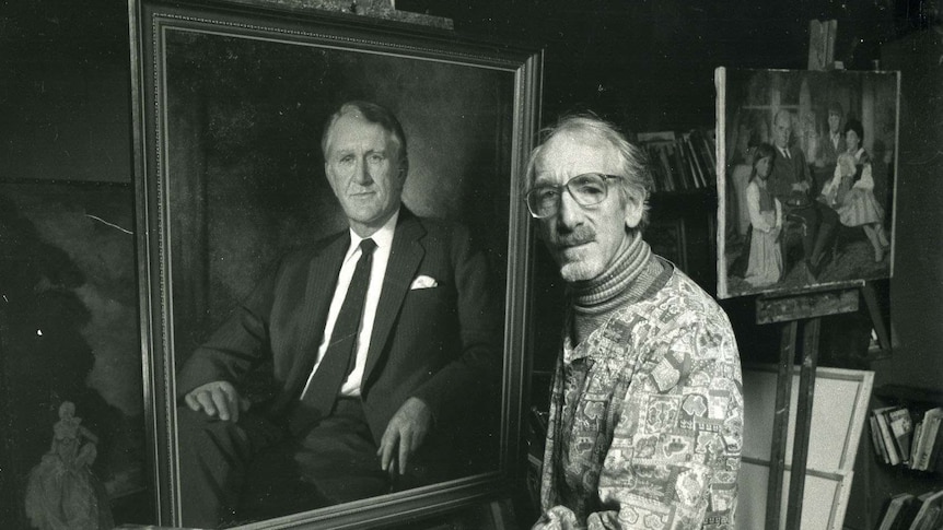 A black and white photo of painter Paul Fitzgerald standing next to a painting of Malcolm Fraser.