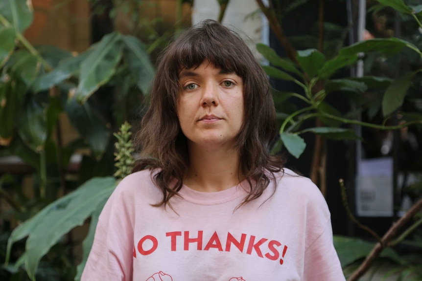 Musician Courtney Barnett in front of greenery in a pink t-shirt