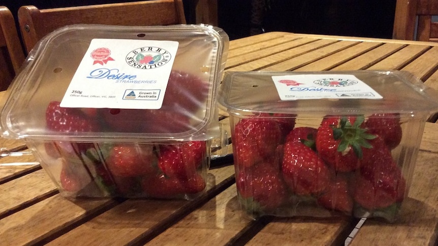 Two packets of strawberries on a wooden table in a secure package.