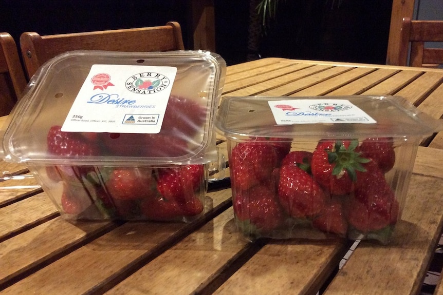 Two packets of strawberries on a wooden table in a secure package.