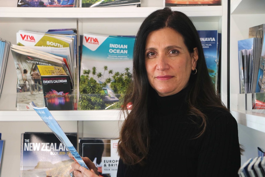 Side profile of a woman holding a travel brochure.