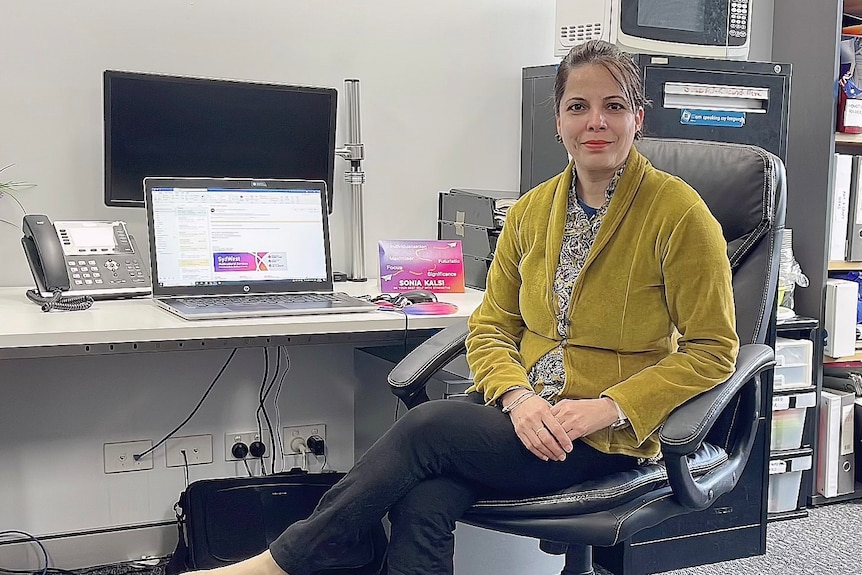 Sonia Kalsi sitting on a chair in an office. 