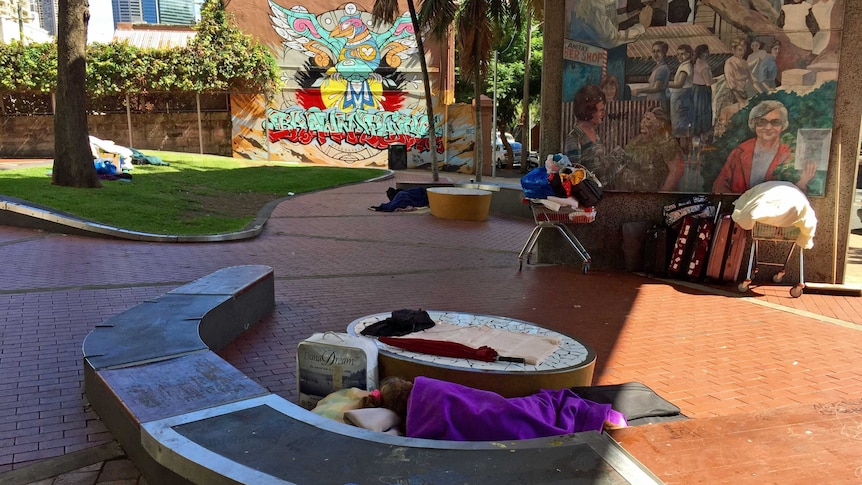 A homeless woman sleeps under a bridge