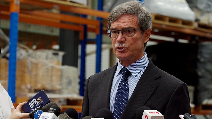 Mike Nahan speaks into a row of media microphones.
