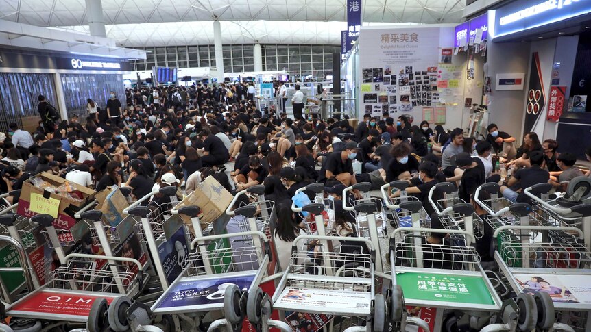 Protesters line up luggage trolleys to block departure gates.