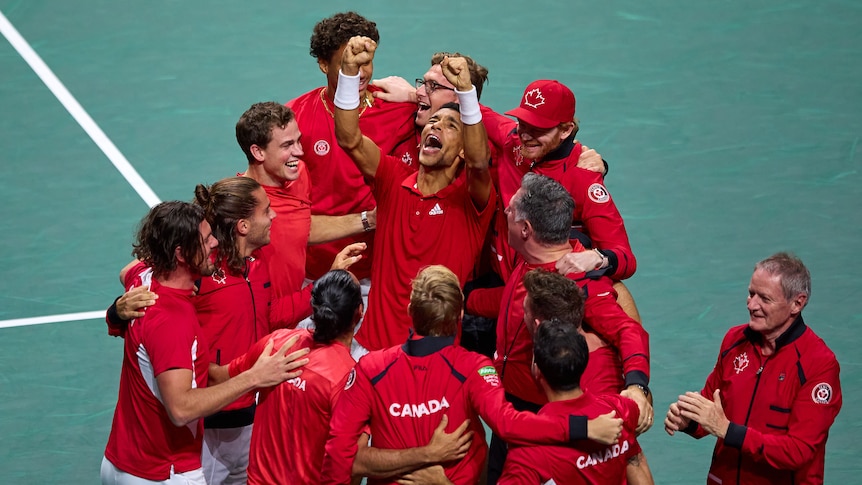 Canada's Davis Cup tennis team celebrate on court in big group huge.