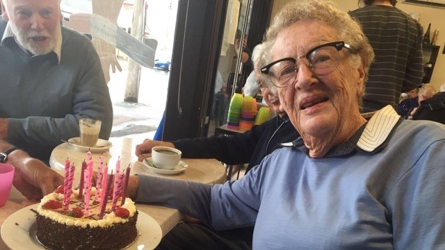 Janet Adams sits in front of a birthday cake.