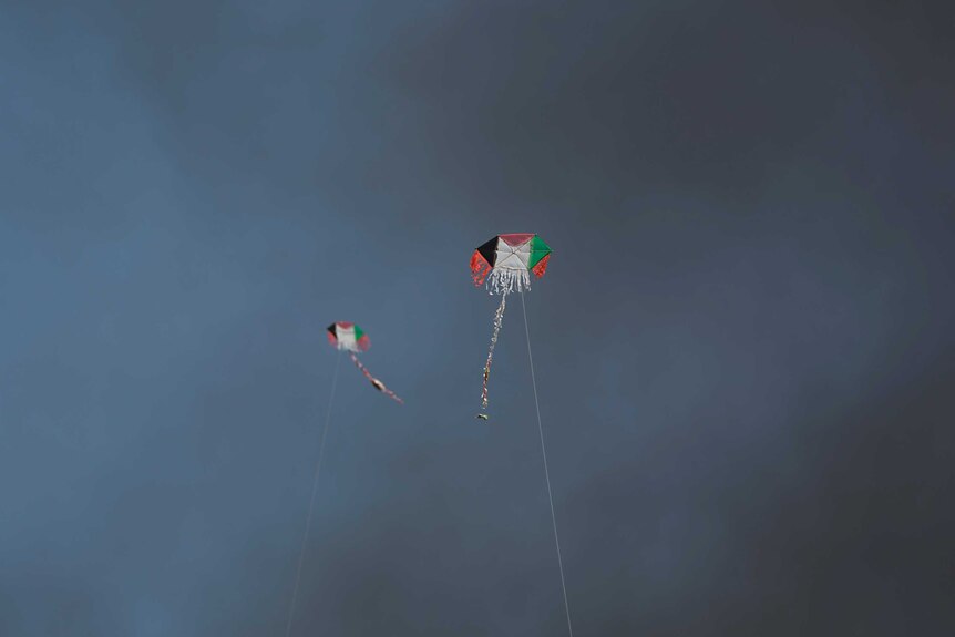 Two kites with Palestinian flag motif are seen in the sky smoke.