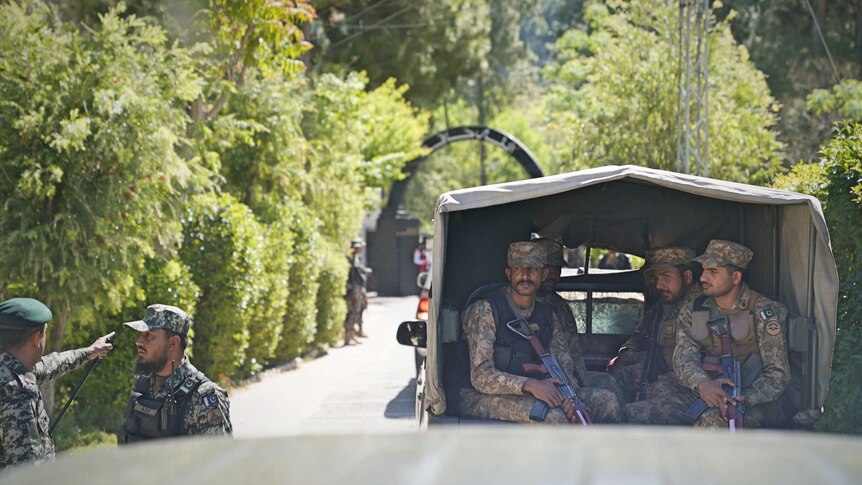 An army truck filled with soldiers holding rifles