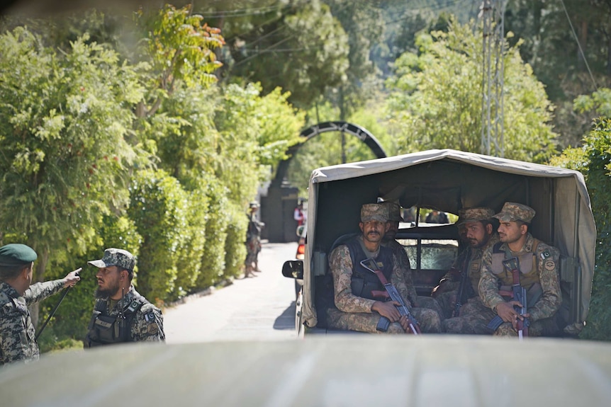 An army truck filled with soldiers holding rifles