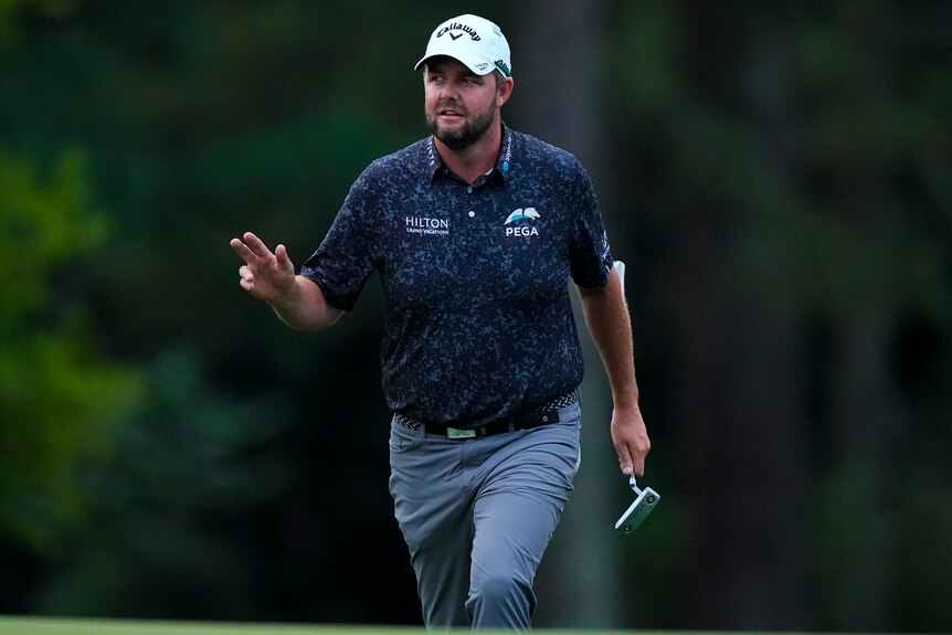 Marc Leishman looks up and raises his hand in thanks to the crowd