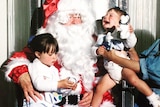 A file photo from the 1980s of two toddlers sitting on Santa's lap. One is crying.