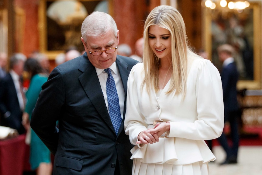 Prince Andrew, an older man, and Donald Trump's daughter Ivanka look down at an object at a busy event at Buckingham Palace.