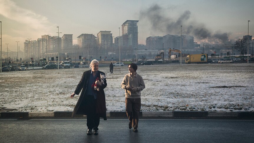 Colour still of Tommaso Ragno and Adriano Tardiolo walking away from an industrial cityscape in 2018 film Happy as Lazzaro.