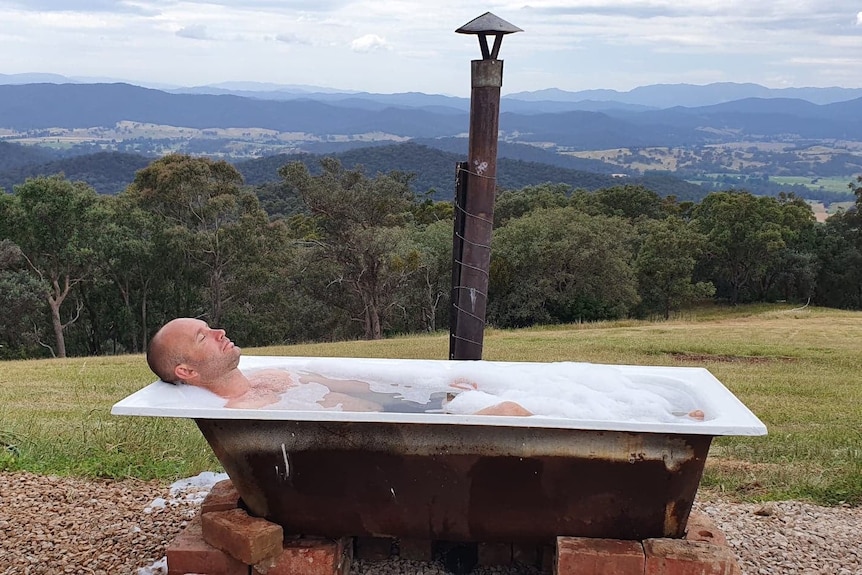 A man in a bath with moutain views