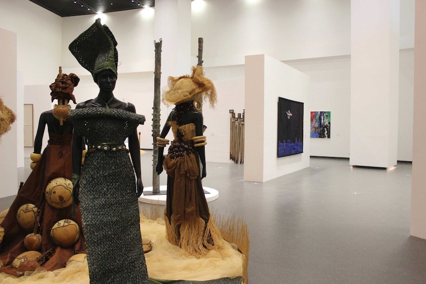 An exhibition space shows three mannequins wearing traditional African textiles.