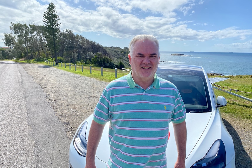 Man stands near park with car in background