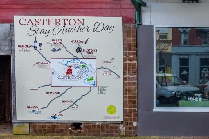 A shop window with a 'Casterton Stay Another Day' sign
