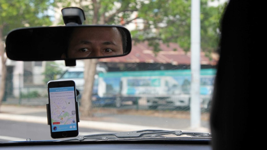 A photo from inside a car that shows the reflection of Yogesh Thapaliya as well as the Hi Oscar app.