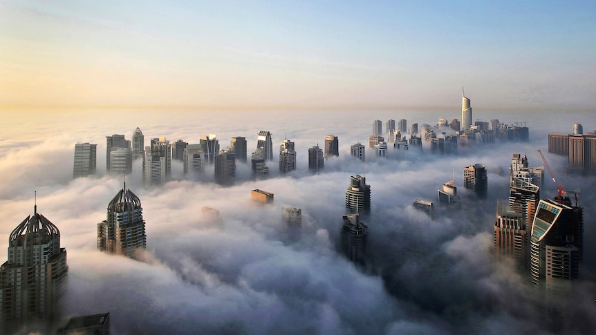 The tops of high-rise buildings in Dubai poke out of a heavy cloud covering the city