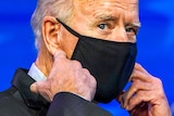 Joe Biden adjusting a black face mask