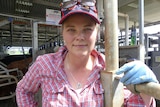 A woman in holding a rail with milking machinery behind her