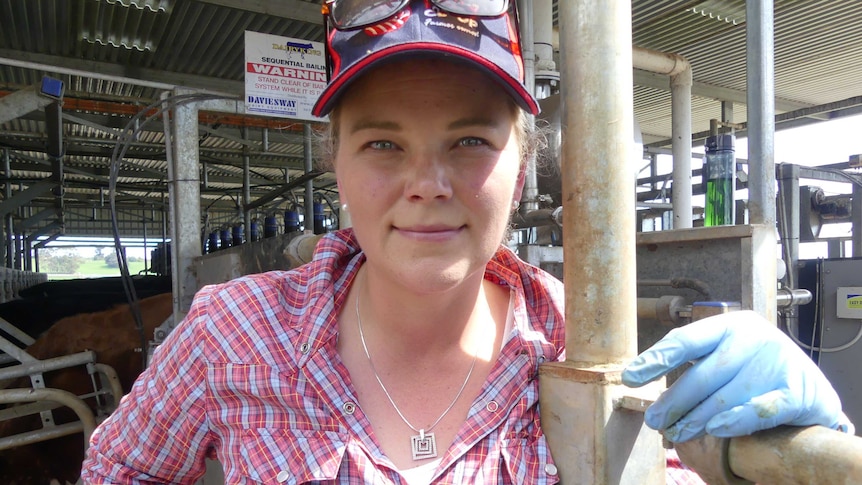 A woman in holding a rail with milking machinery behind her