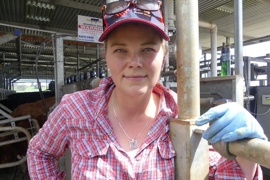 A woman in holding a rail with milking machinery behind her